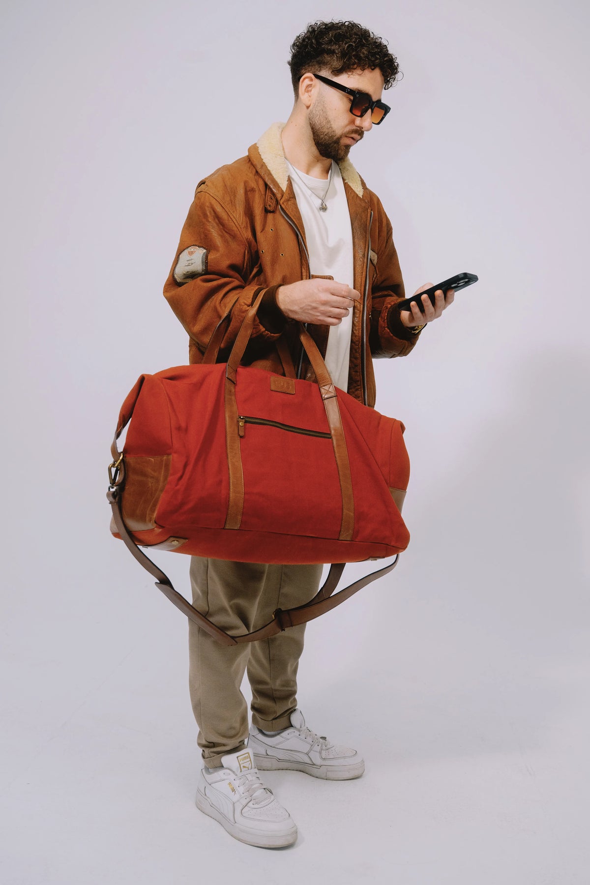 Duffel bag carried comfortably while man checks his phone