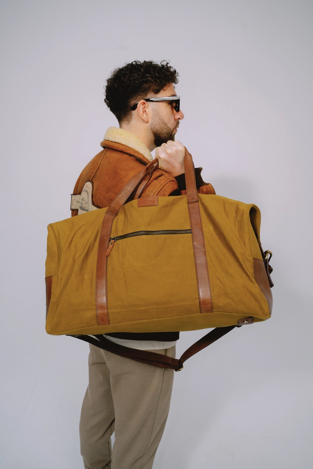 Ochre travel duffle bag worn over the shoulder while standing