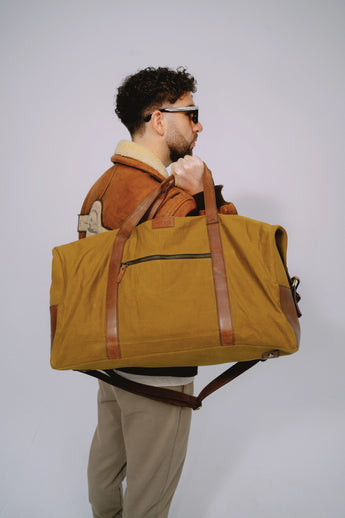 Ochre travel duffle bag worn over the shoulder while standing