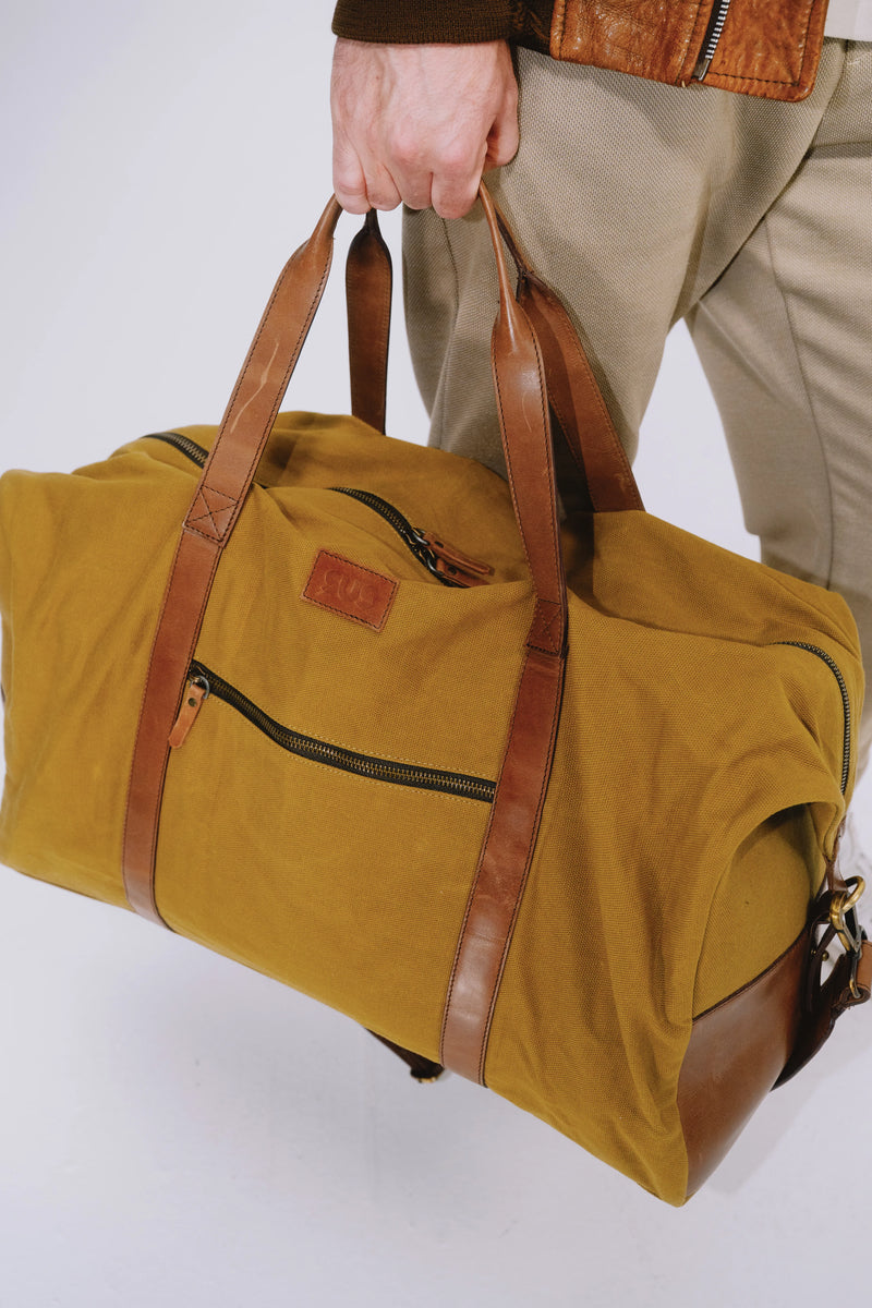 Golden ochre travel duffle bag held in hand
