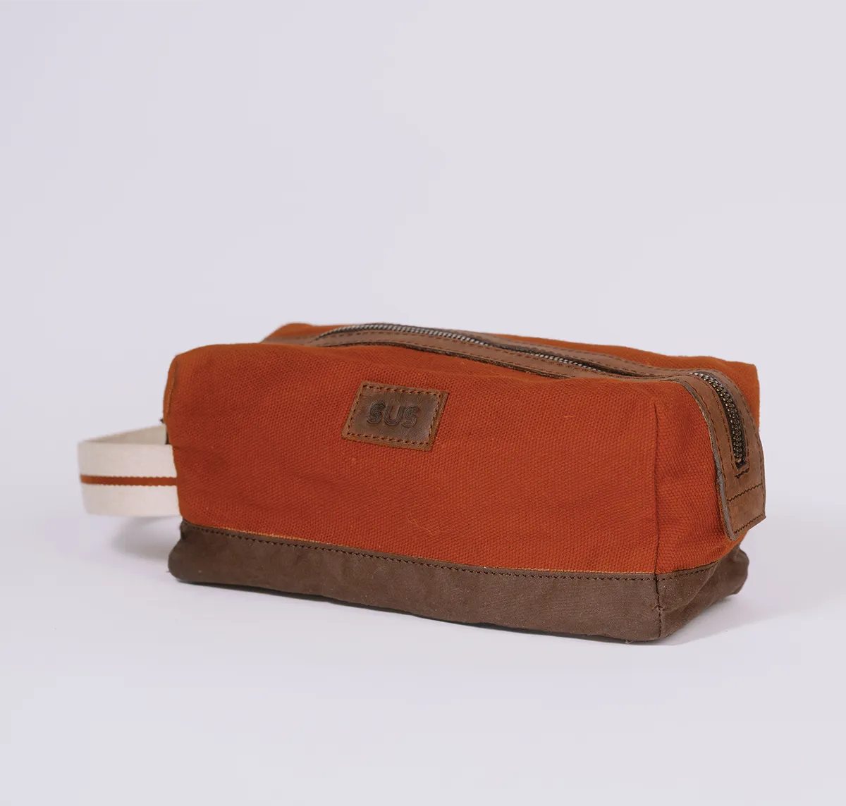 Angle photo of a canvas toiletry bag in rusty red color
