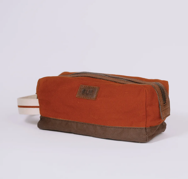 Angle photo of a canvas toiletry bag in rusty red color