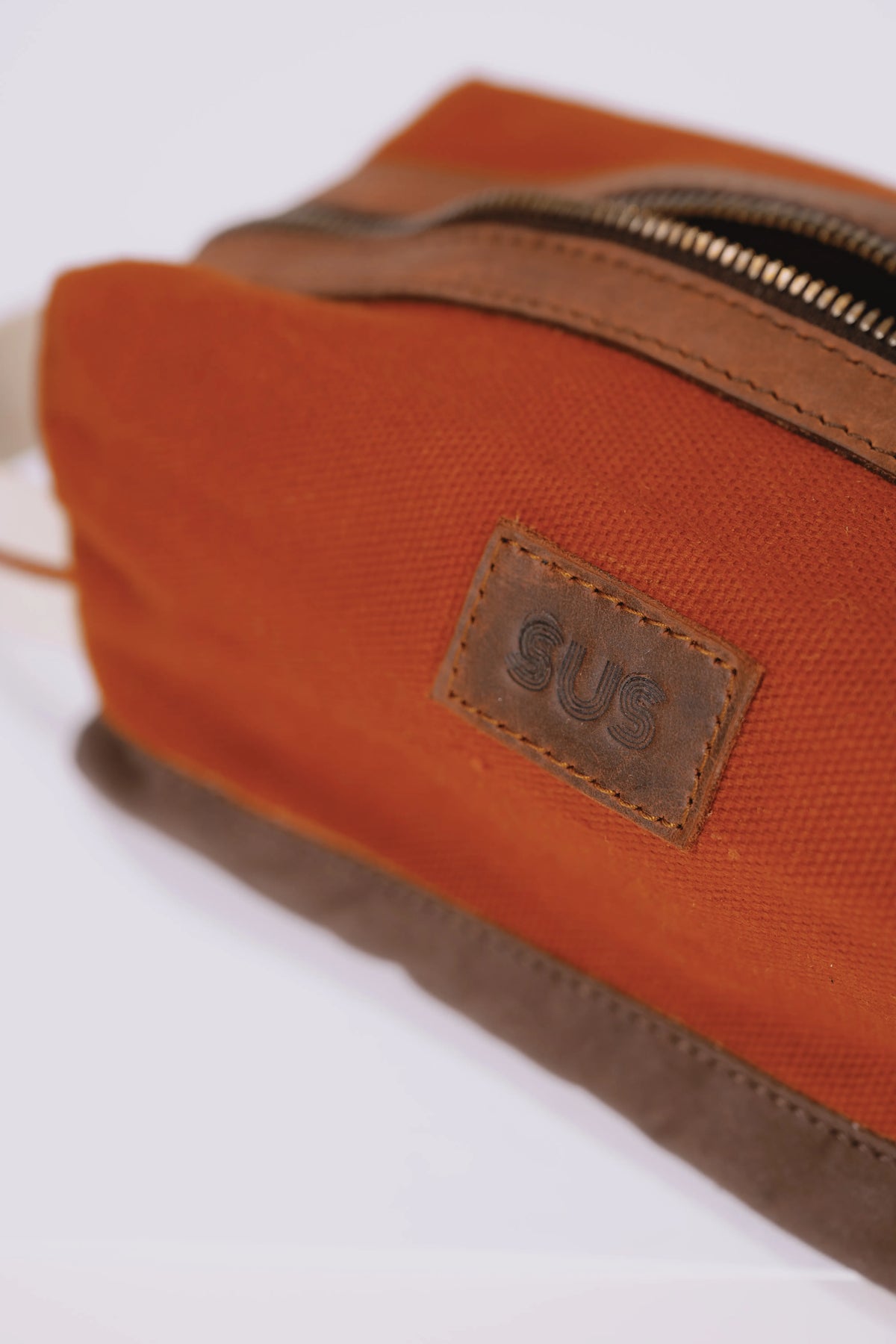 Leather SUS logo on a rusty red toiletry bag