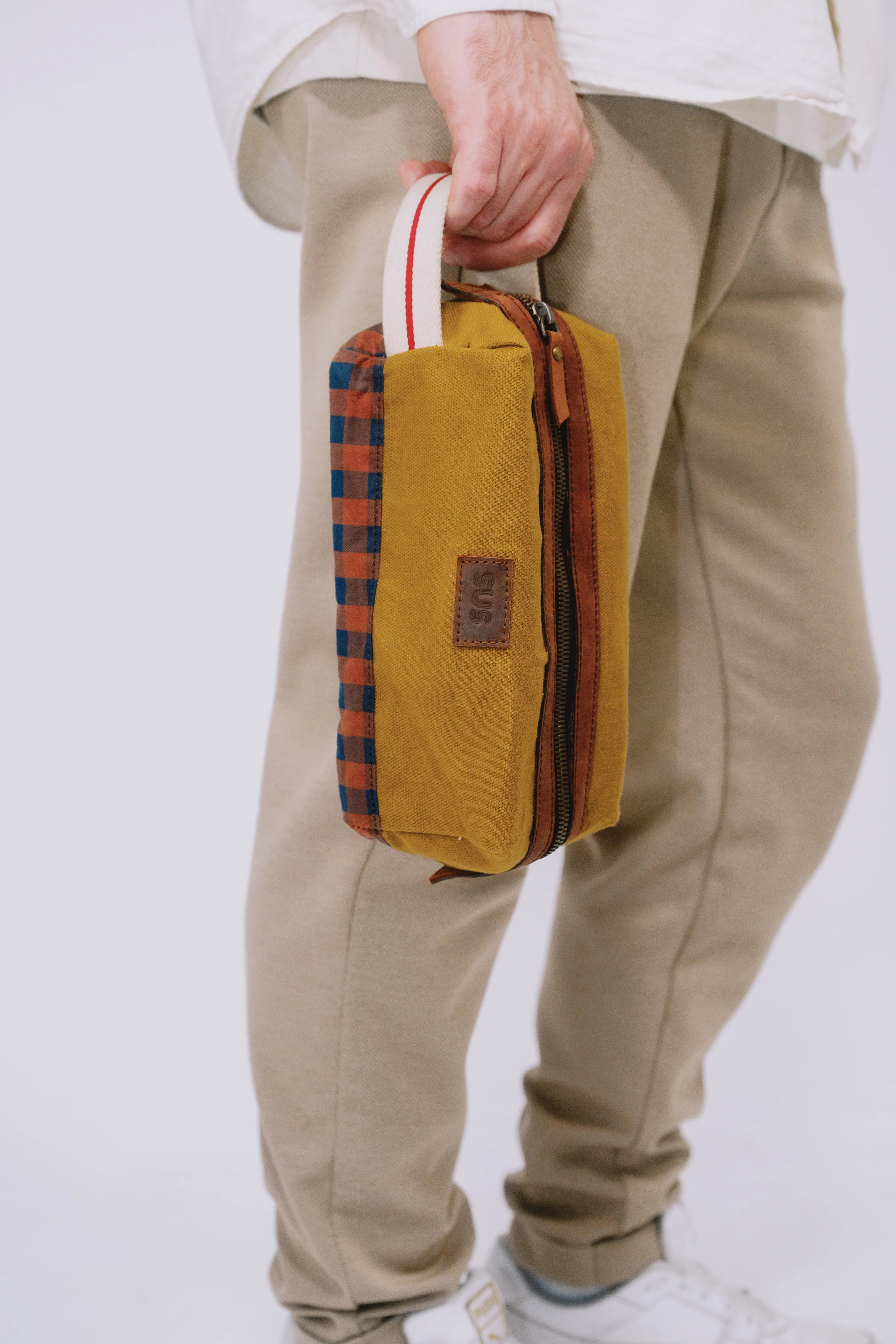 Golden Ochre toiletry bag held by strap – compact travel kit