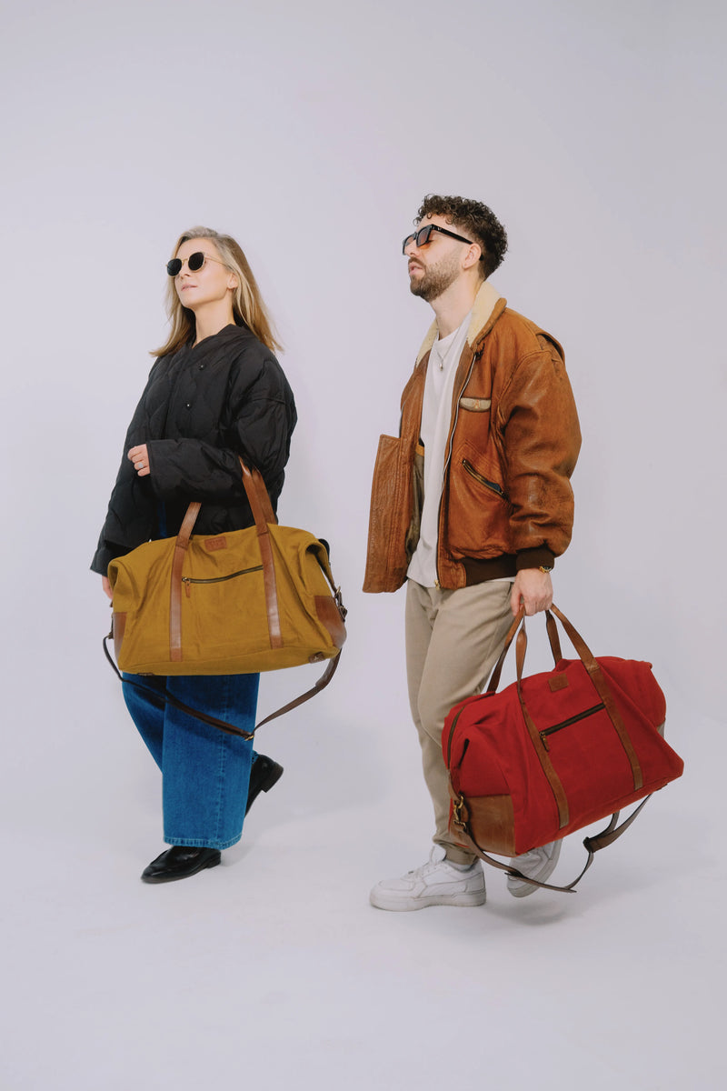 Two people with travel duffle bags walking in the studio